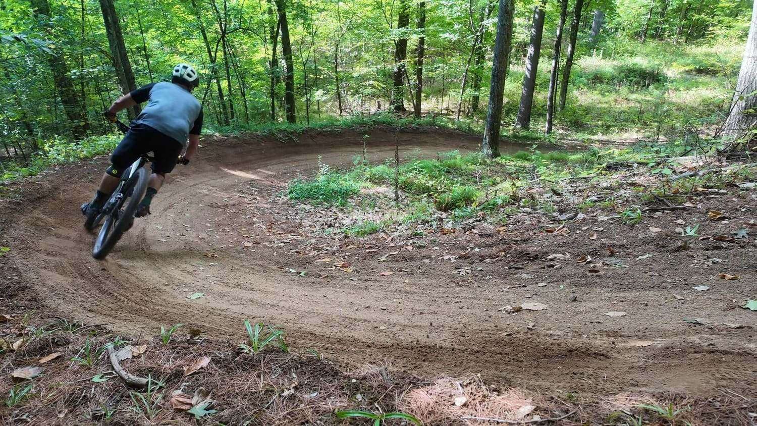 A rider leaning through a bermed dirt corner in the woods