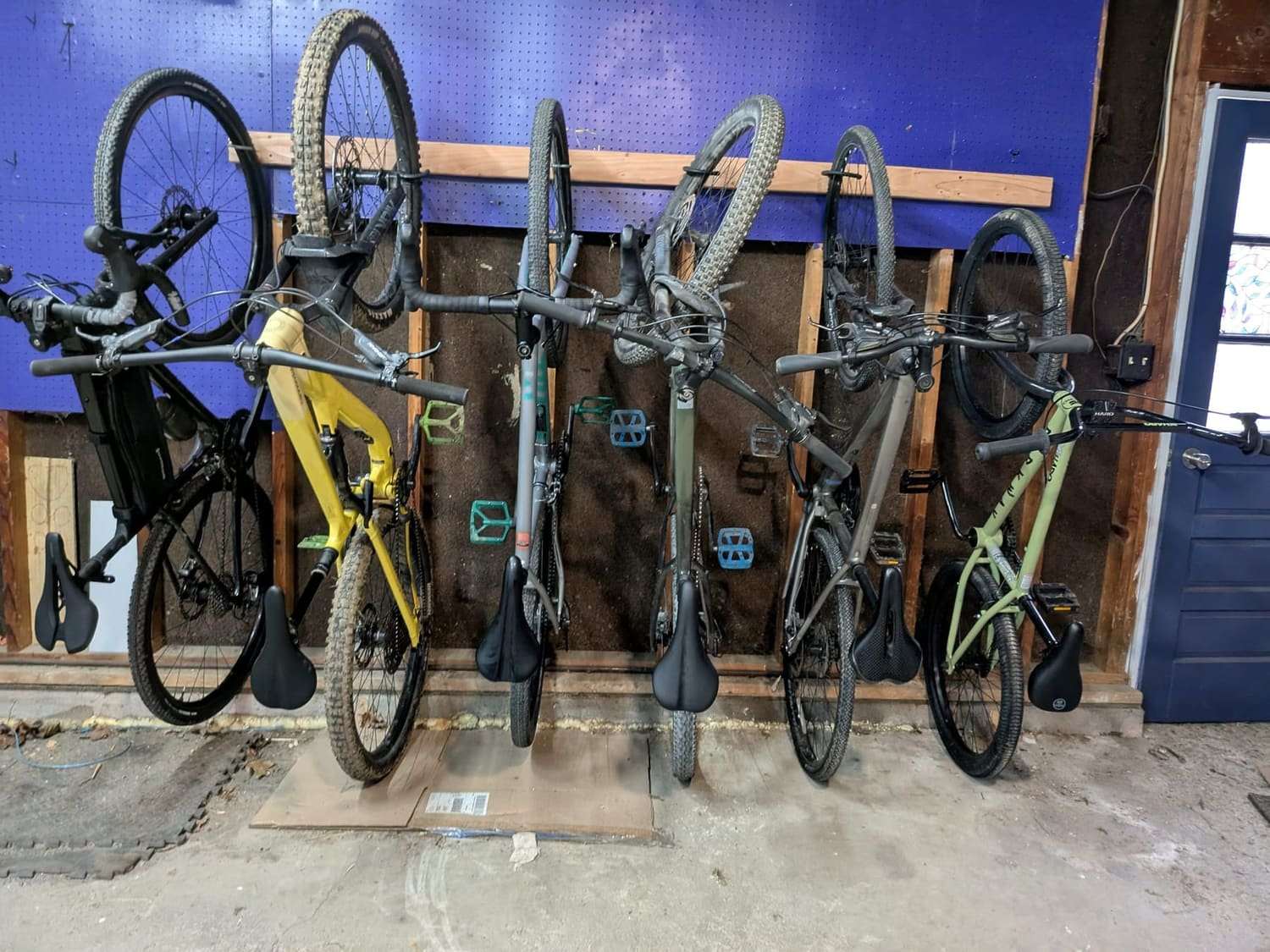 Five bikes racked against a garage wall