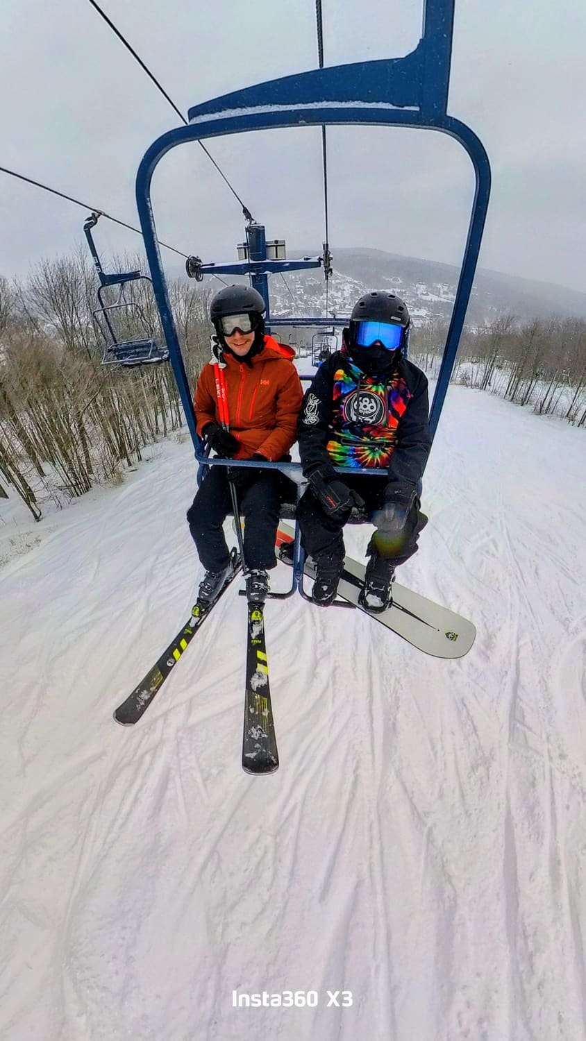 Two skiers riding a chairlift over a snowy slope