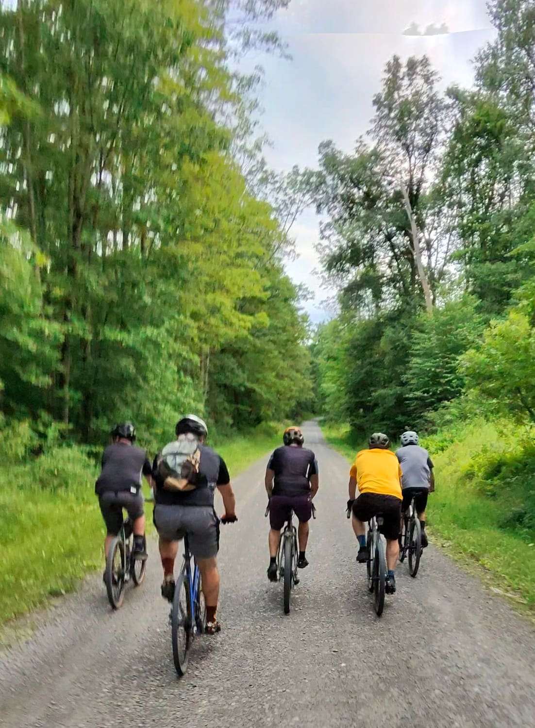 Five riders spread across a gravel road in evening light