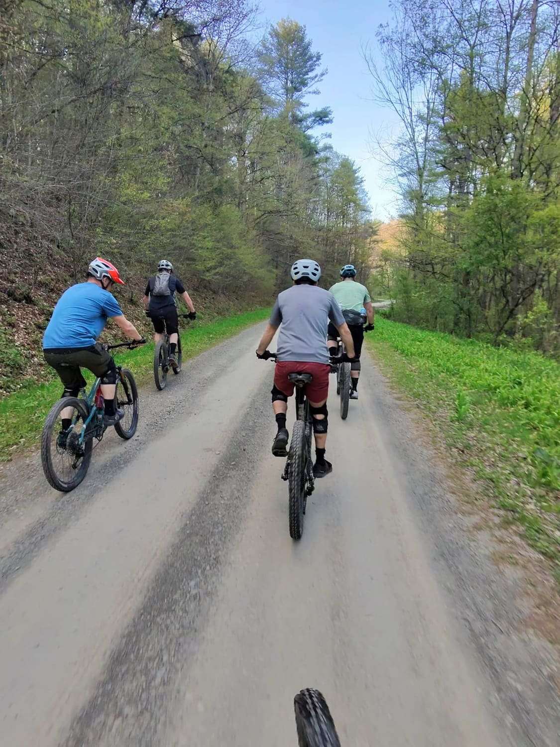Four riders climbing a gravel road in a line