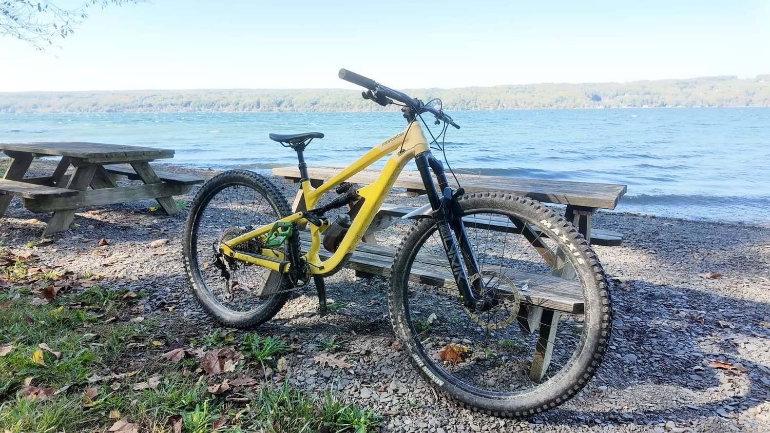 A bike parked at a picnic table on the shore of a long lake