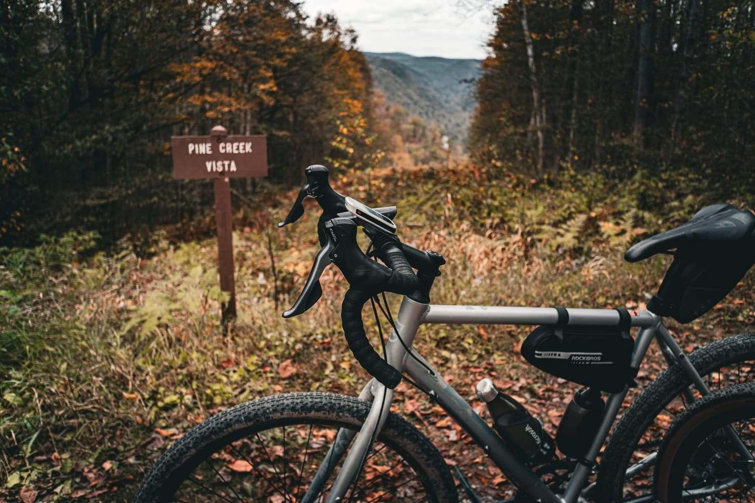 A gravel bike propped beside a Pine Creek Vista trail sign in autumn