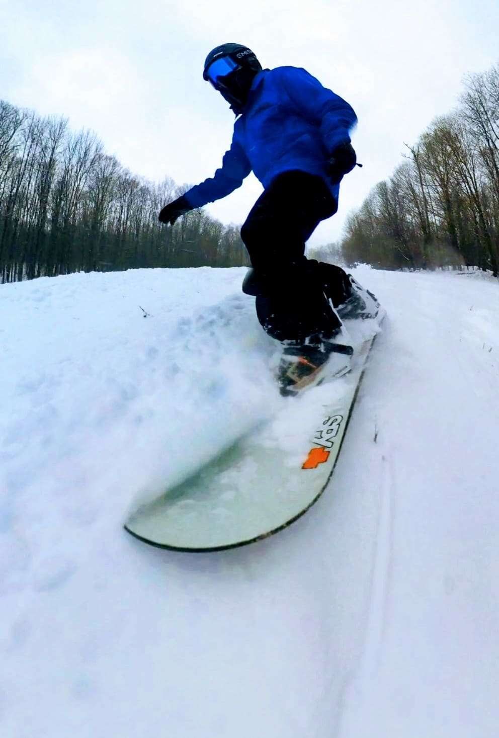 A snowboarder in the air over a snow covered trail