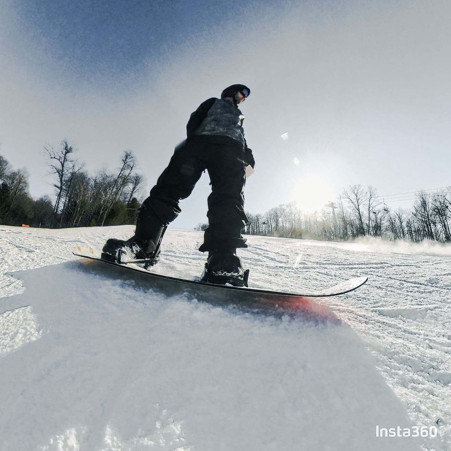 A snowboarder carving down a groomed run on a grey winter day